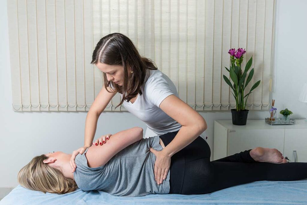Clinician assessing a patient’s spinal movement in a bright examination room